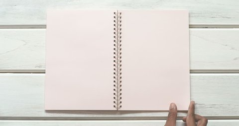 A male hand open diary paper 3 page  on the white wooden desk, top view and overhead shot use for blank template book mock up to add any text content