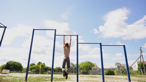 young athletic fitness woman working out at outdoor gym doing pull ups at sunrise Video de stock