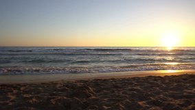 Empty beach at sunset or sunrise, waves slowly splashing on the shoreline, relaxing wide angle video background