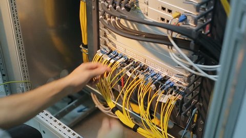 Network engineer in server room works with optical patchcord and optical module. Data centr