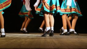 Closeup of female legs of children dancing cheerfully on stage. Real time hd video footage.