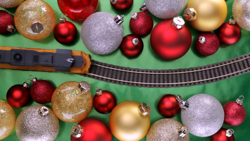 Toy electric train passes over curvy track though colorful christmas tree