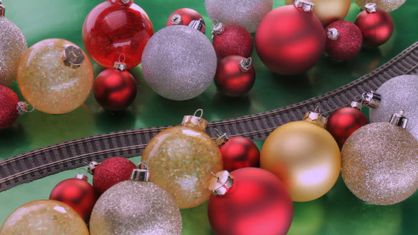 Toy electric train passes through colorful christmas tree decorations shot at