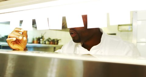 Chef looking at order list while serving food at order station in resturant