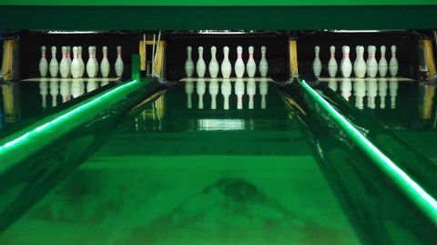 Playing bowling game on colorful alley. Bowling ball knocks down 7 pins. Process of bowling game. Bowling strike competition