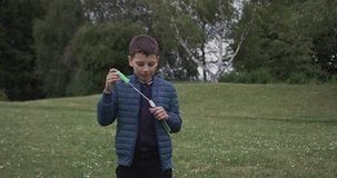 Young boy boy blows a bubbles in the garden, in Ultra HD video 4k (4096x2160)