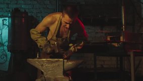 Blacksmith is forging metal detail in smithy