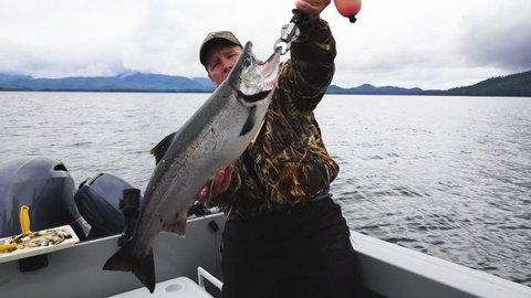 Fisherman holding up a King or Chinnook Salmon in the fertile waters of  Southeast Alaska. Salmon Fishing is big sport both recreational and commercially