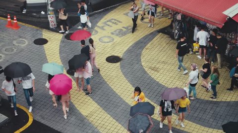 Seoul - July 2017: People walking with umbrellas on a rainy day at Hongdae district. Elevated view.
