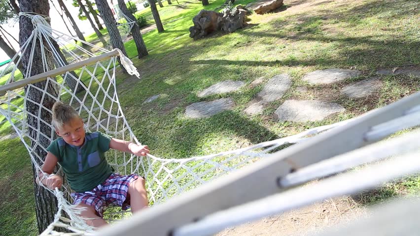 Point of view shoot of cute funny white cheerfully playing alone outside during vacations. Happy kid laying and relaxing in hammock hanging on trees in summer pine wood. Real time full hd video.