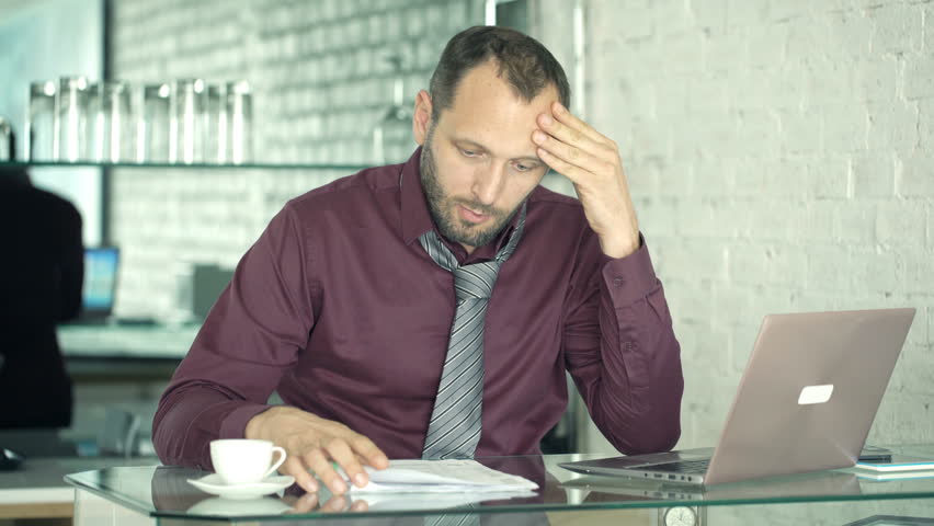 Upset, unhappy businessman working with documents and laptop by table in kitchen
 | Shutterstock HD Video #29365504