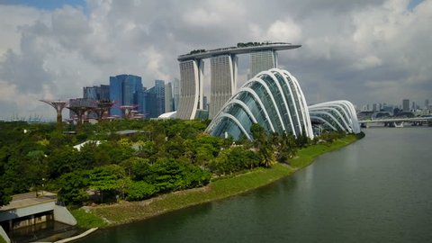 SINGAPORE - MAY 2017: Aerial view of beautiful glass structures and botanical gardens, flying towards luxurious Marina Bay Sands resort hotel and Singapore skyline