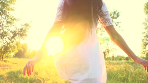 Beautiful young woman running on field, enjoying nature outdoors. Beauty sexy brunette girl with long healthy hair in short white dress running and spinning. Slow motion 240 fps 4K UHD video 3840x2160