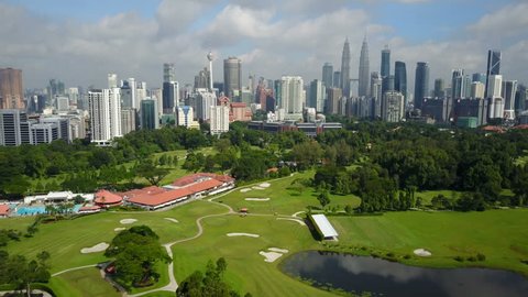 KUALA LUMPUR, MALAYSIA - MAY 2017: Aerial drone shot flying over golf course towards Petronas twin towers and other commercial and residential skyscrapers of downtown Kuala Lumpur, Malaysia