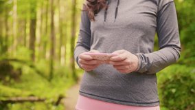 Midsection Of Sporty Woman Typing On Smartphone In Forest