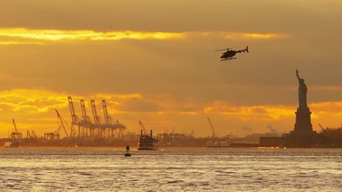 Beautiful sunset over New York Upper Bay and Statue of Liberty with ferry boat and flying helicopter