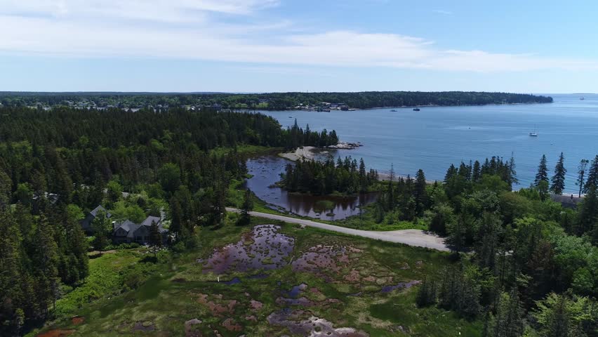 A moving aerial view along the Bernard shoreline within Bass Harbor on Mt Desert Island Maine