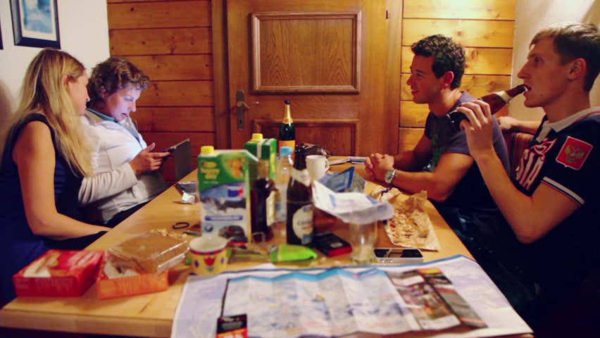 Two men sit at table and drink beer, then women use tablet pc