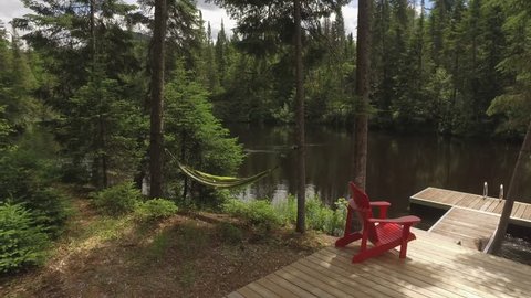 beautiful scene of muskoka chairs and hammock at lake cottage