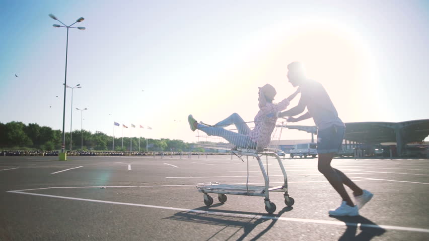 Young friends having fun on shopping trolleys. Multiethnic young people racing on shopping cart. slow motion Royalty-Free Stock Footage #29413315