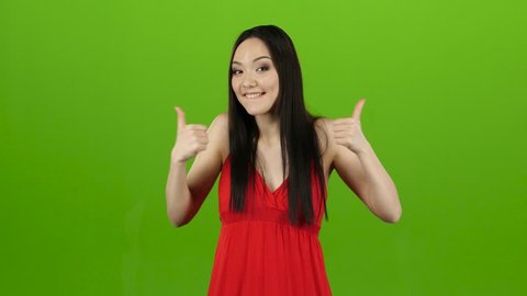 Girl in the spacious room is having fun and showing a thumbs up. Green screen