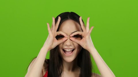 Girl of asian appearance has fun and makes different grimaces. Green screen