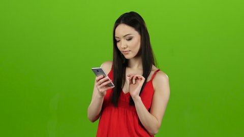Asian girl does selfie, she smiles while looking at the camera. Green screen