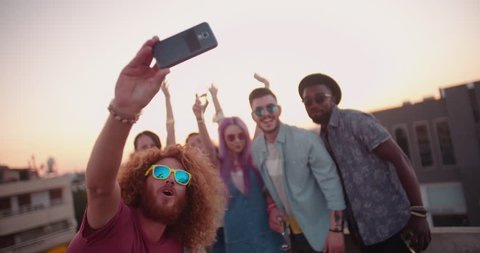 Multi-ethnnic hipster friends partying with champagne and taking selfies at rooftop summer party