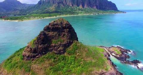 Small Coastal Tropical Island Surrounded by Turquoise Ocean with Mountain Ridge in Background - Oahu, Hawaii Aerial Footage