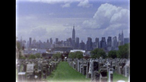 May 2016. First Calvary Cemetery in Queens, New York. Manhattan skyline over rows of graves. Jammed film camera effect. Hand held camera work. 8mm film footage. Filmed with Super8 film camera.