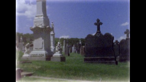 May 2016. First Calvary Cemetery in Queens. Tombstones, graves and sculpture of an angel on the column. 8mm film footage. Filmed on super8 film tape, with Super8 camera.