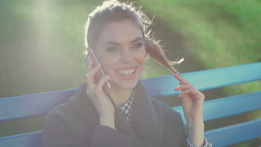 Beautiful young woman communicates on the phone in the park