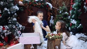 Two little girls at a Christmas tree prepare a gift for the grandmother. Granddaughters pack a white shawl as a present to their beloved grandmother in a gift box. - Powered by Shutterstock - Get 15% off with code: PIKWIZARD15
