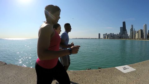 Multi Ethnic American male and females running by Lake Michigan Chicago city for training sport workout