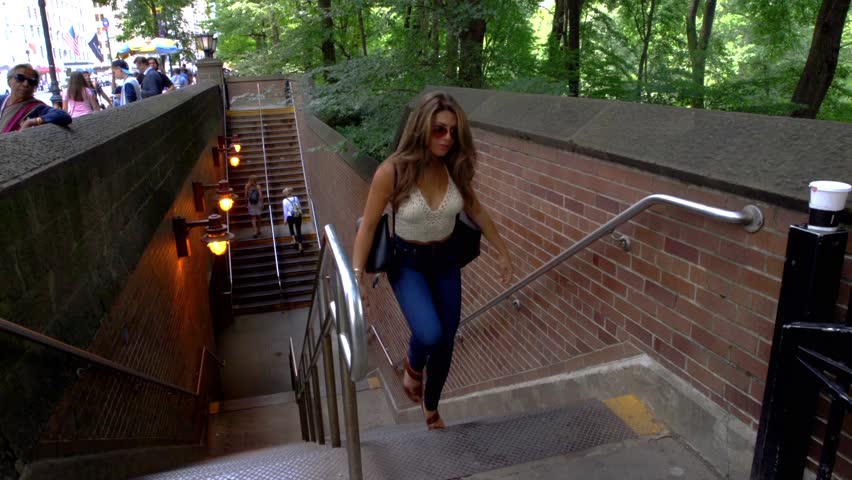 Young Caucasian Woman With Long Brunette Hair Walks Out Of The New York City Subway System And Up A Flight Of Stairs