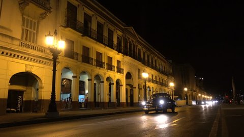 HAVANA, CUBA - FEBRUARY 2017: Modern and vintage cars drive through central Havana at night, creating a mysterious atmosphere