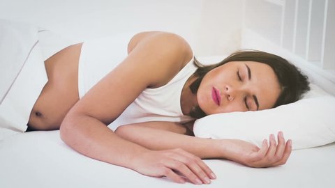 Young smiling woman sleeping with ease in bed in morning