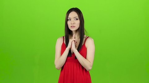 Girl is asian, hoping for a win and crossing her fingers. Green screen. Slow motion