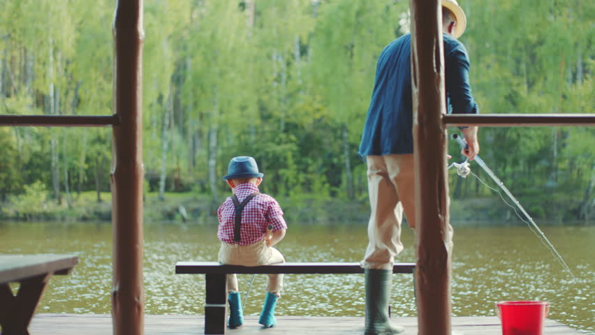 Old man and his grandson in straw hats are fishing on the river at summertime. They are holding rods in their hands Royalty-Free Stock Footage #29451415