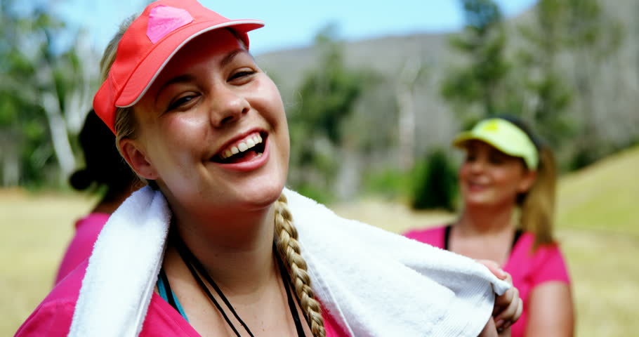 Portrait of Caucasian female trainer standing with towel around her neck in the boot camp