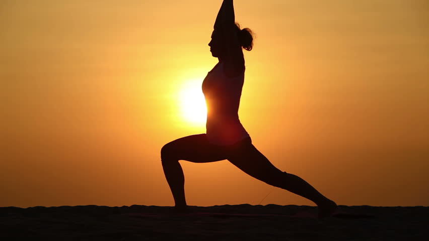 Slim woman doing yoga over orange sun
