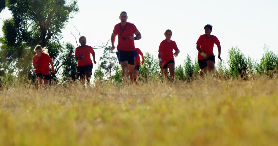 Trainer training kids in the boot camp on a sunny day
