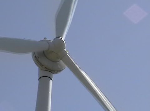 Medium shot of a rotating white power-generating windmill.