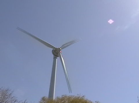 Far Shot of a rotating white power-generating windmill.