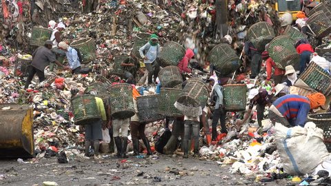 JAKARTA, INDONESIA - APRIL 2017: People scavenge for items to recycle at garbage dump site in Jakarta, tough working conditions in Indonesia