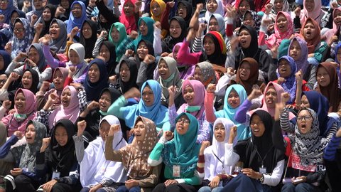JAKARTA, INDONESIA - APRIL 2017: Veiled Muslim school girls chant 'Allahu Akbar' while clenching fists, colorful headscarves, Islamic religion in Jakarta, Indonesia
