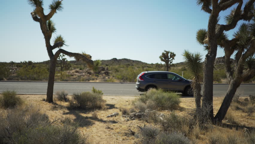 An SUV on the side of a empty desert highway for green screen or chroma key. Out of focus or defocused shot for compositing or keying.