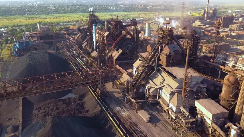 Blast furnace view from the air. Old factory. Aerial view over industrialized city with air atmosphere and river water pollution from metallurgical plant near sea.