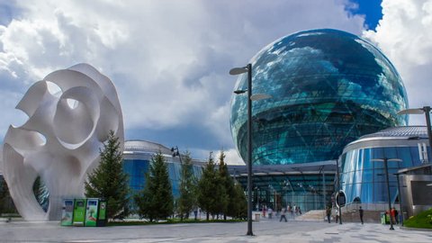 Kazakhstan, Astana, July 19, 2017. People walk around Nur Alem pavilion. Day time static timelapse of Nur Alem pavilion at the Astana Expo 2017, with a cloudy sky. The largest world spherical building