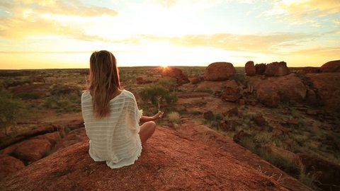 Caucasian female meditating at sunrise
Young woman at the devil's Marbles sitting on a boulder exercises yoga at sunrise. Devils Marbles Conservation Reserve, Northern Territory, Australia.